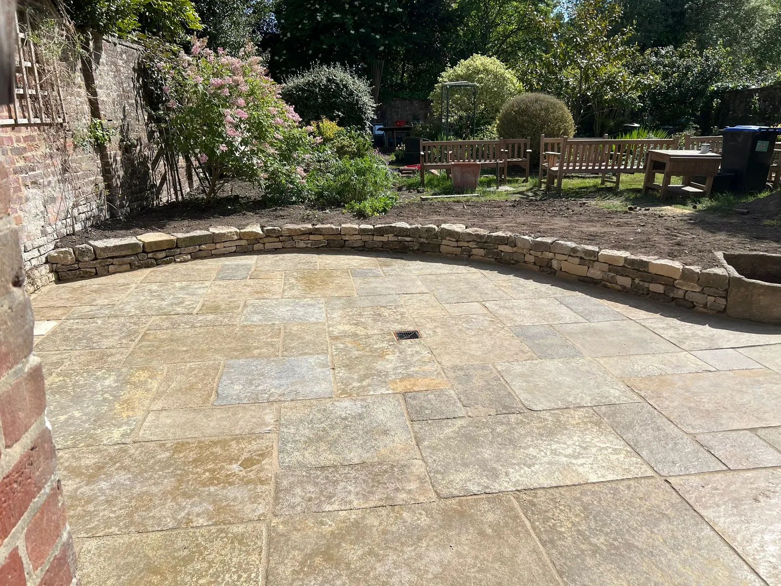 A circular sandstone patio enclosed by a curved stone border