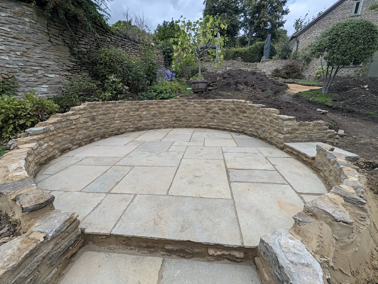 A circular sandstone terrace enclosed by a curved stone retaining wall