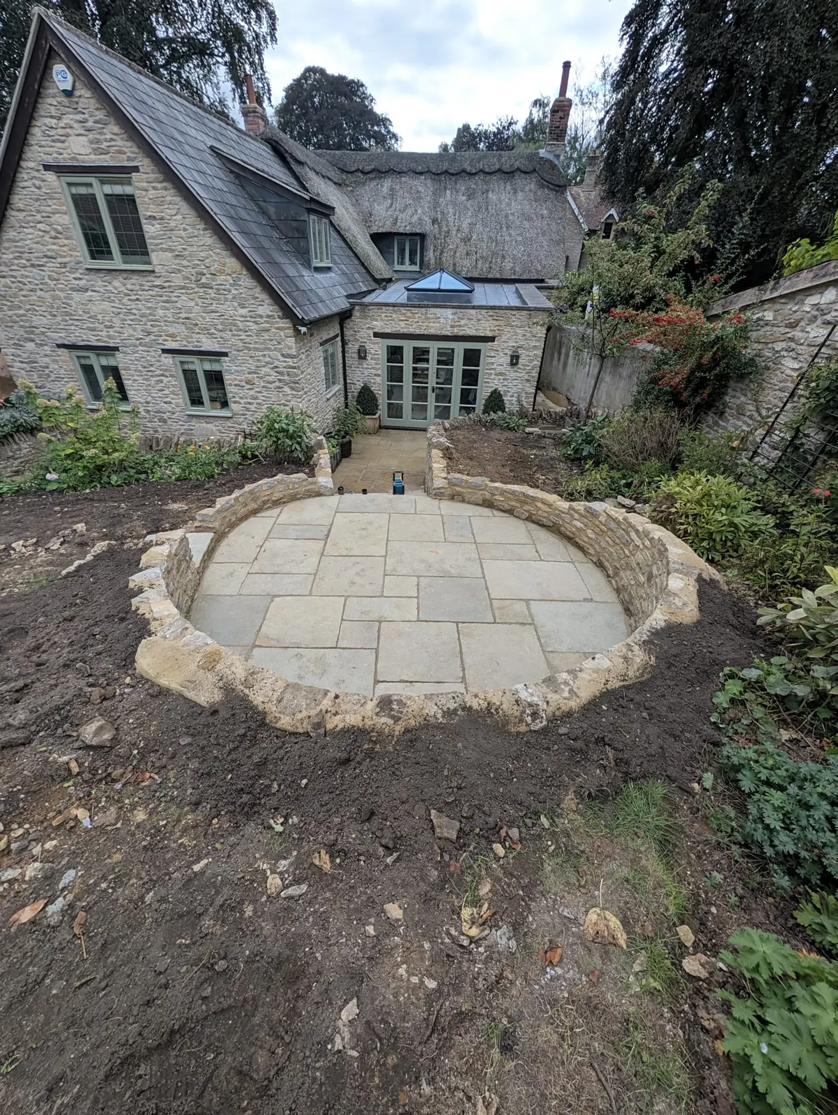A circular stone terrace in front of a traditional cottage