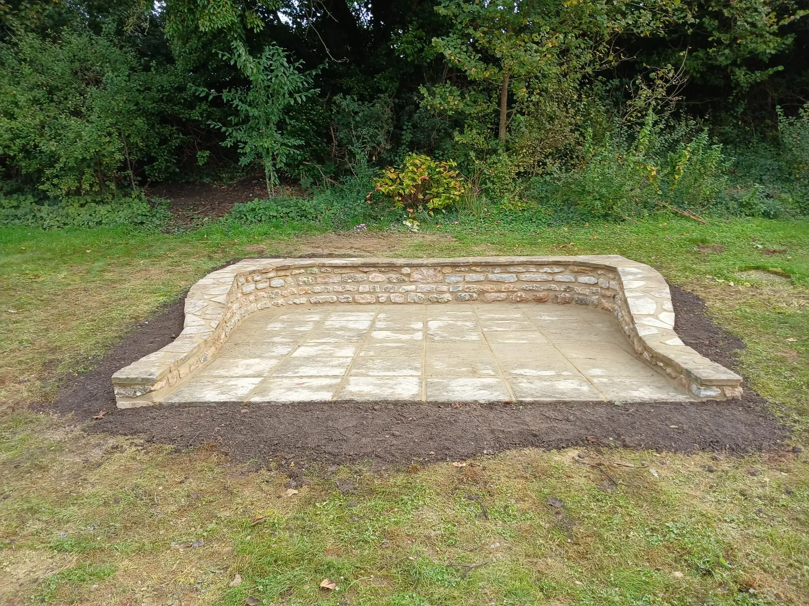 A curved stone garden seat built into a lawn