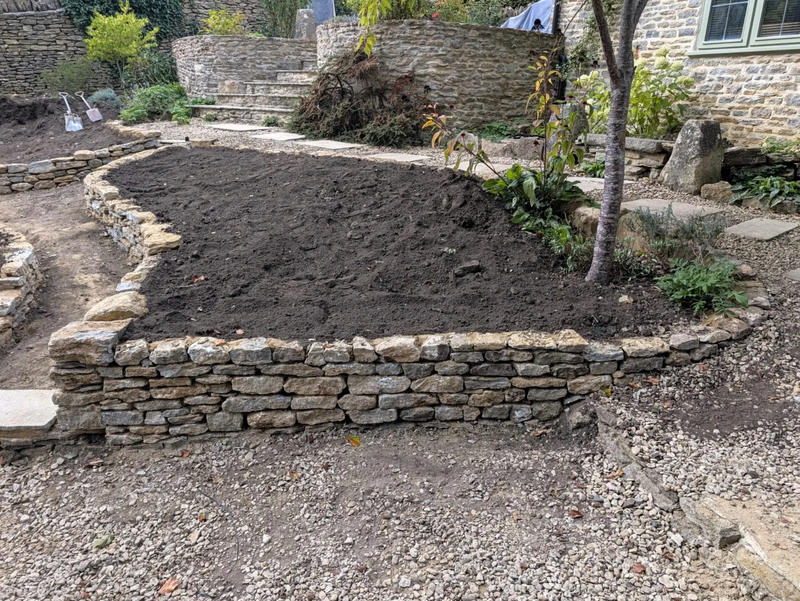 A curving stone retaining wall around a newly planted slope