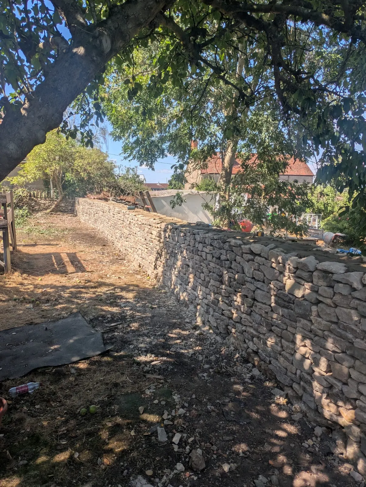A close view along a new dry stone boundary wall in dappled shade