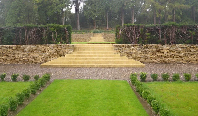 Broad stone steps rising between clipped lawns and low stone walls