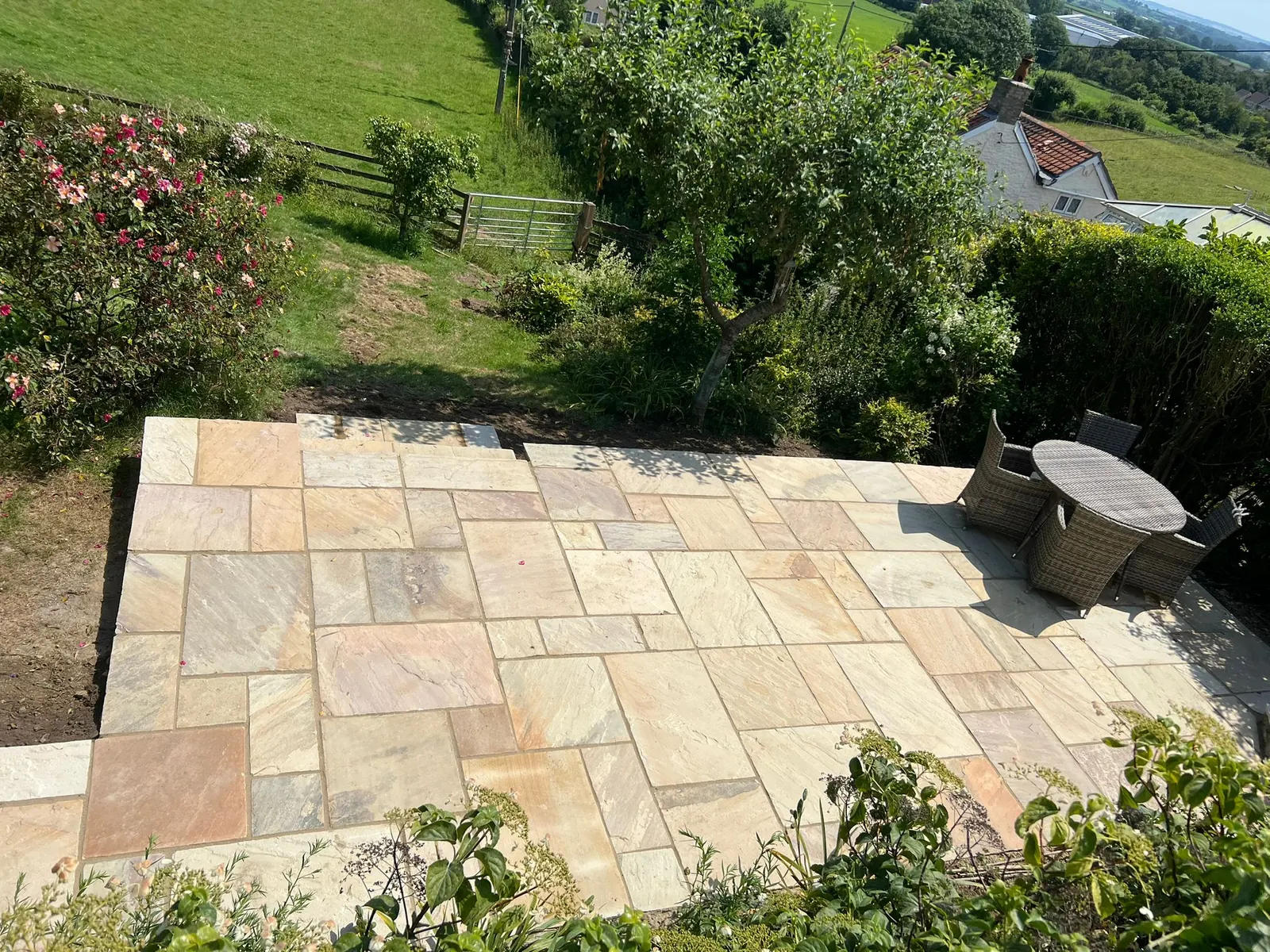 A sandstone terrace overlooking a sloping country garden
