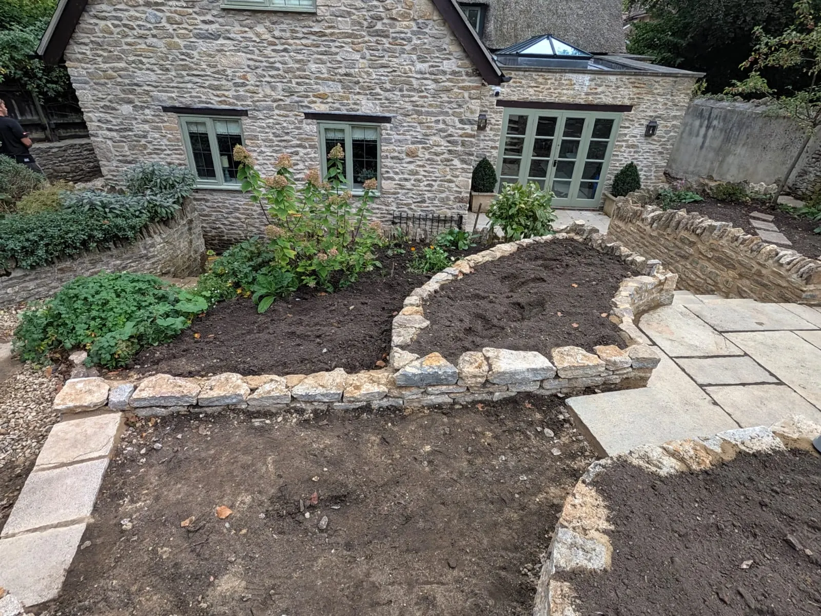 A landscaped cottage garden with curved paths and stone-edged beds