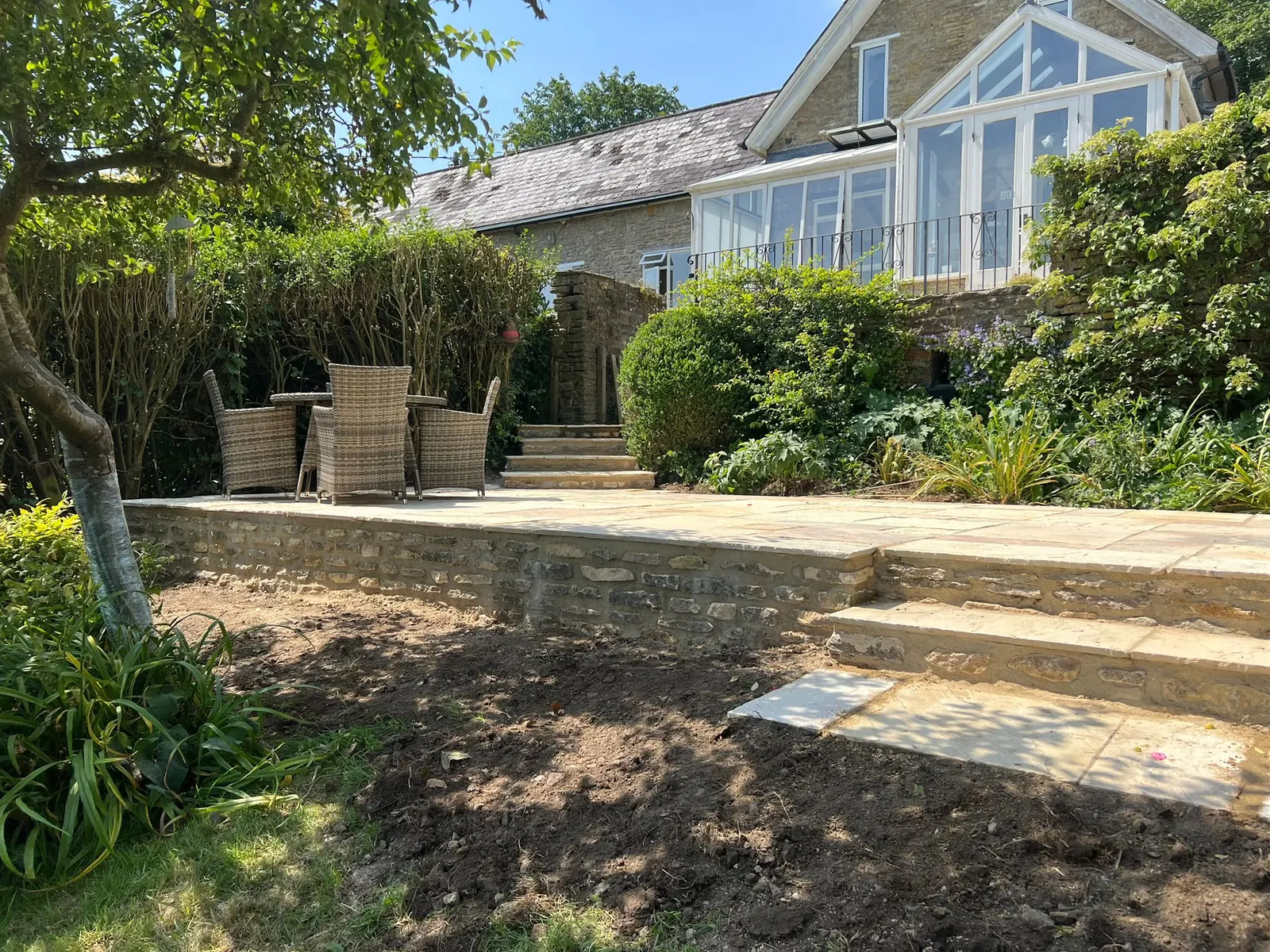 A landscaped garden with a sandstone terrace and broad steps