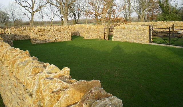 A curved dry stone wall around a new lawn
