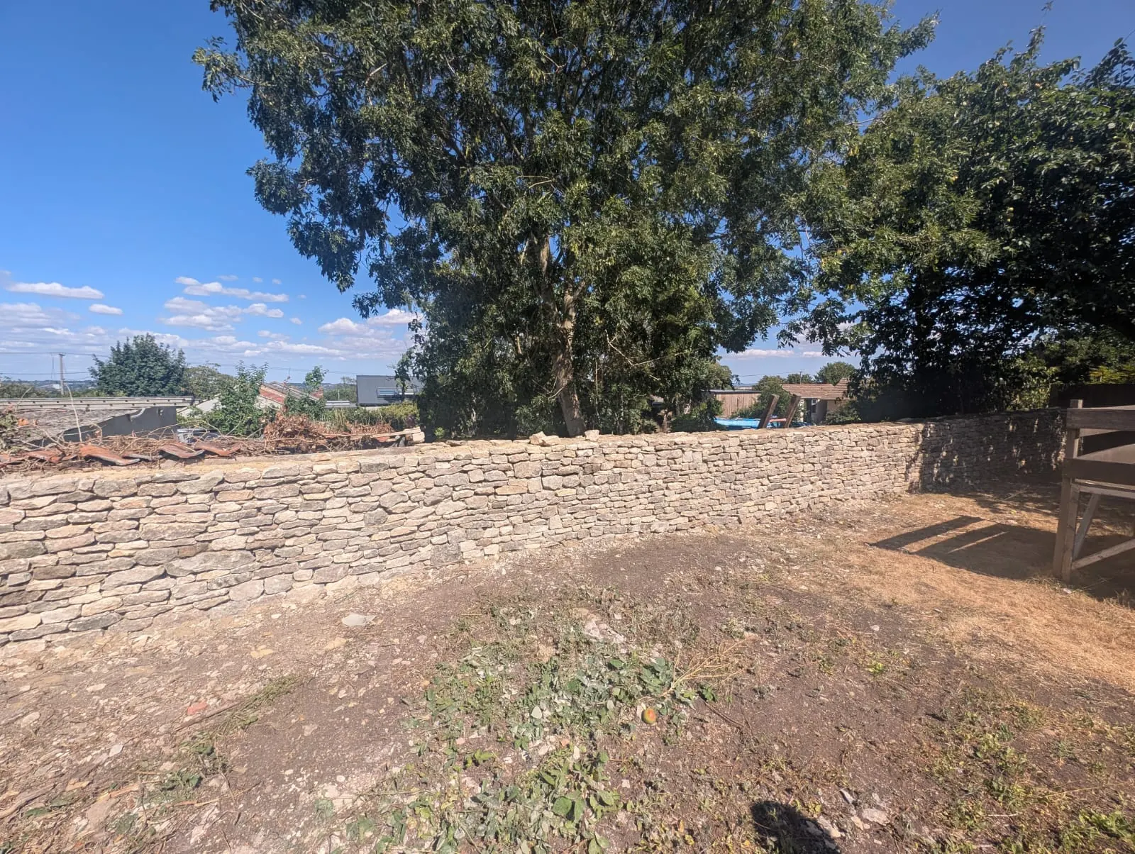 A long newly built dry stone boundary wall beneath mature trees