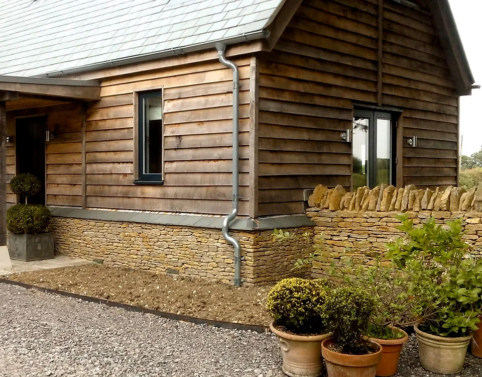 An oak-clad building with a new dry stone wall and gravel forecourt