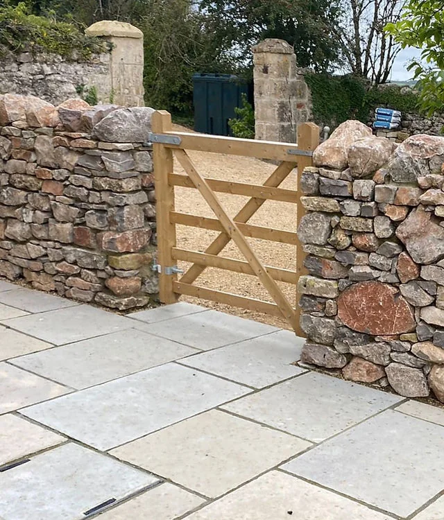 Stone paving leading to an oak gate set in a stone wall