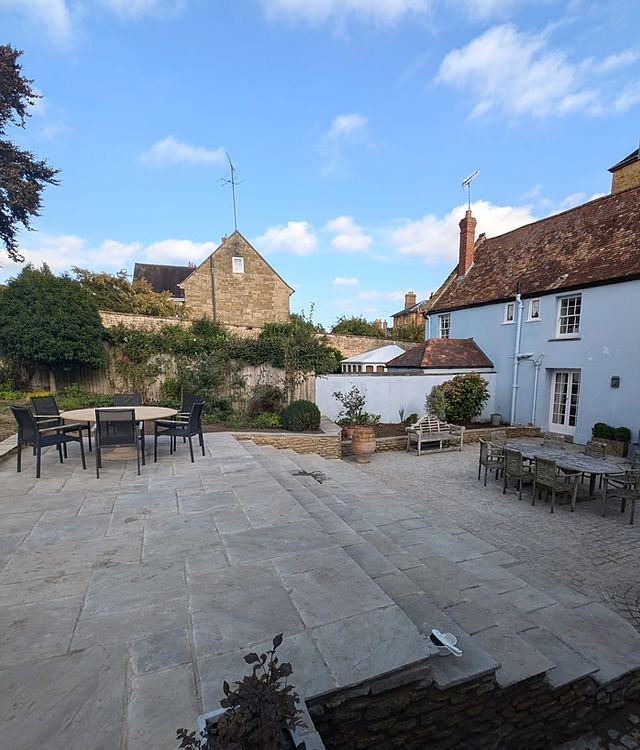 A large paved courtyard with seating beside a white-painted cottage