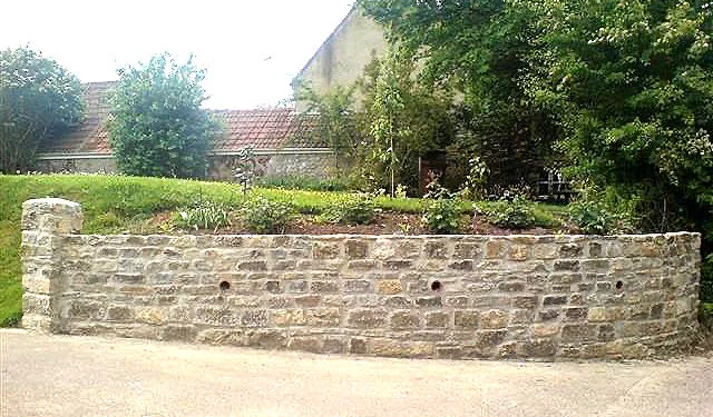 A curved stone retaining wall in a planted garden
