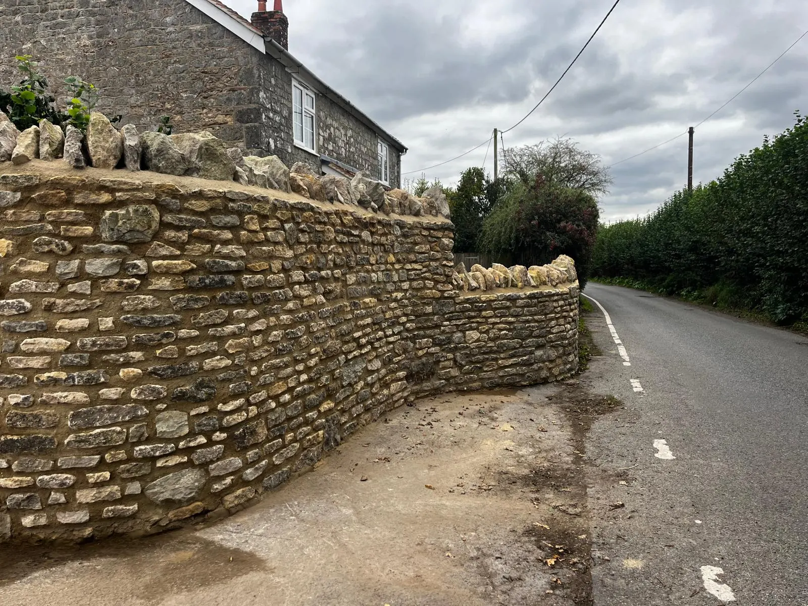 A finished coursed stone wall beside a narrow country road