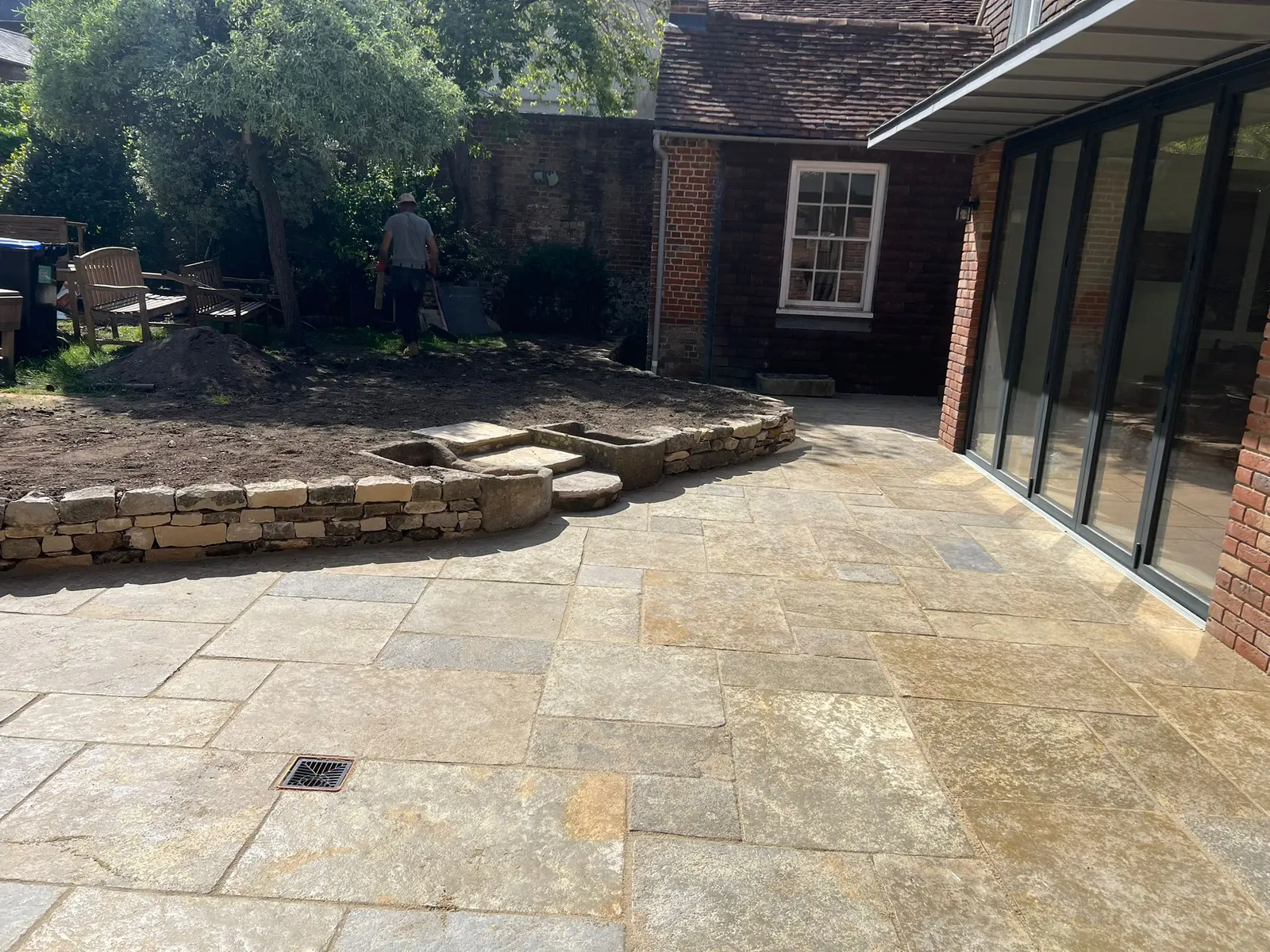 A sandstone courtyard beside a glazed garden extension