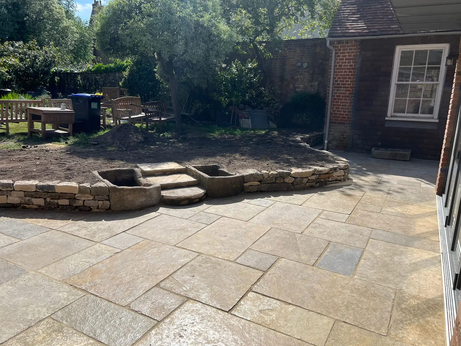 A sandstone patio with curved steps and a low stone border