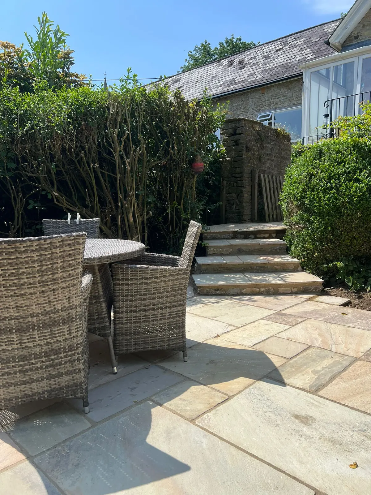 A sandstone patio leading to garden steps and a raised terrace