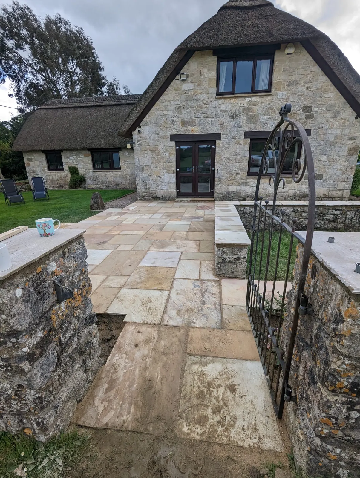 A sandstone terrace and stone walls outside a traditional cottage
