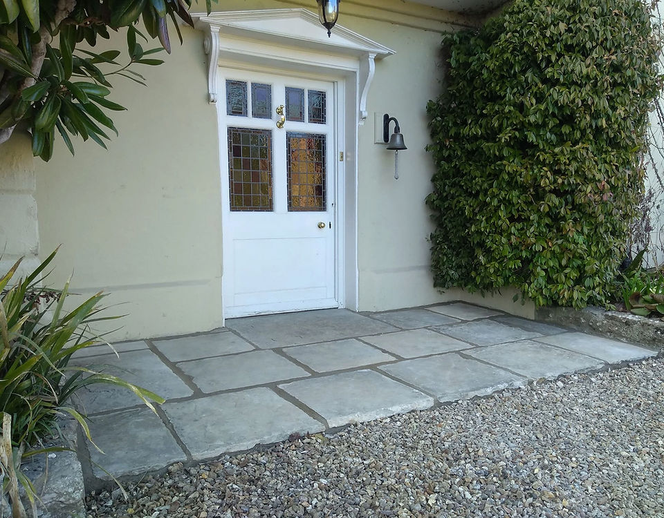 Grey stone flags and gravel in front of a white front door