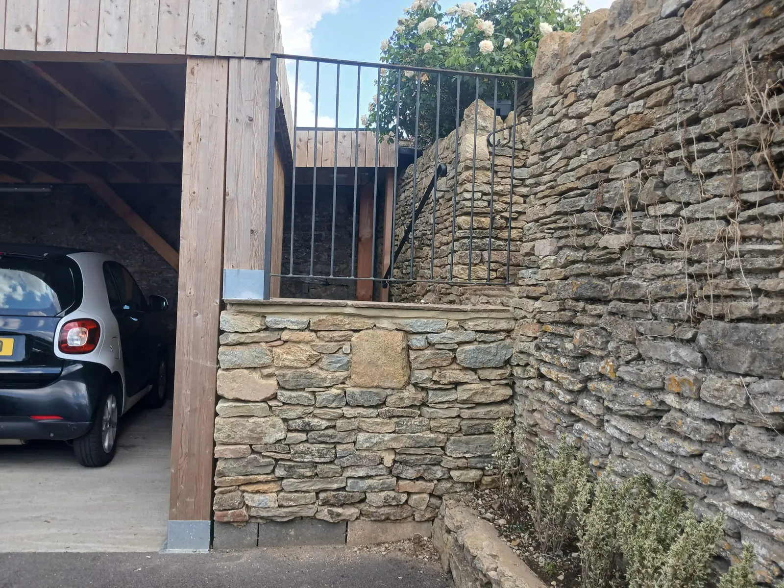 A stone garage wall finished with a black iron railing