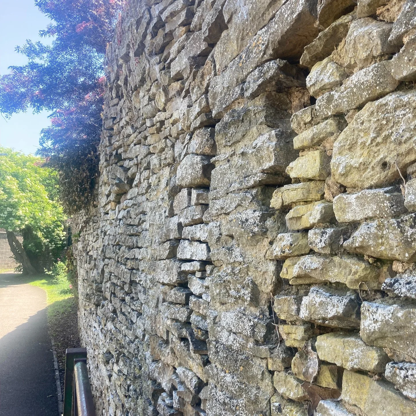 A tall dry stone wall rising beside a lane