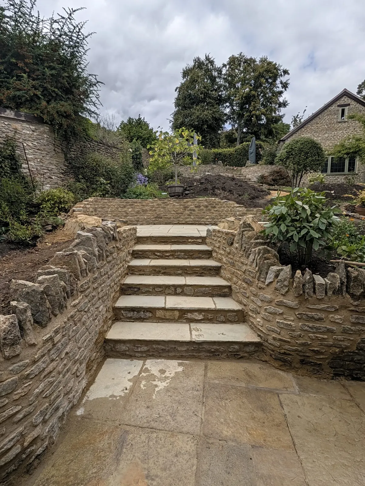Stone steps rising between retaining walls in a terraced garden