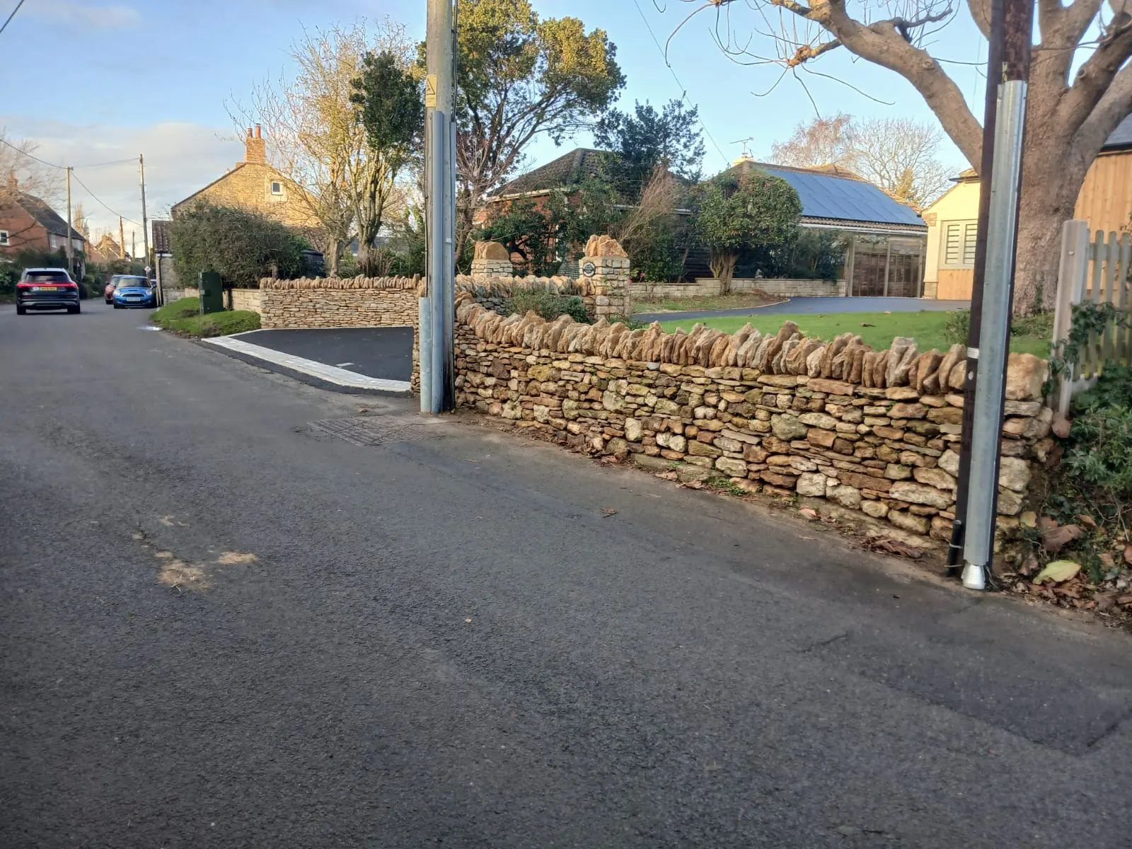 A dry stone boundary wall following a village road