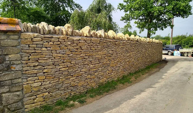 A long dry stone wall beside a country lane