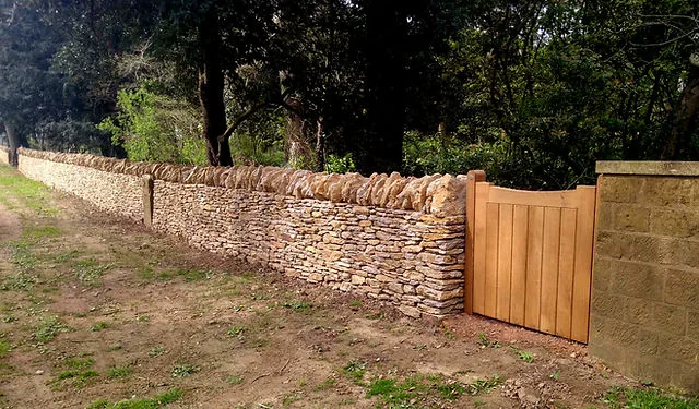 A dry stone wall with a new oak gate beside a lane